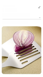 Close-up of mirror polished stainless steel slotted spatula with purple onion reflection