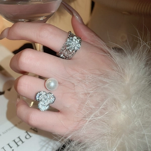 Gros plan sur une bague fleur en zircon et bague perle portée pour un look élégant