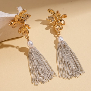 Détail de boucles d'oreilles fleur dorée avec perles et pompons de chaînes argentées