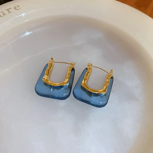 Detailed close-up of vintage U-shaped earrings with gold metal and deep blue resin