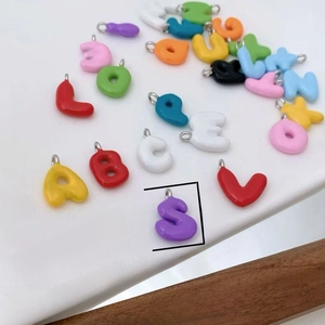 Detail shot of colorful enamel alphabet charms, gold plated copper DIY jewelry pendant.