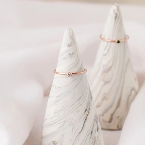 Nahaufnahme minimalistischer Roségoldringe mit weißen und grünen Zirkonia auf Marmor