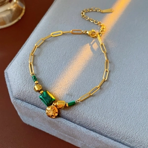 Vue détaillée du bracelet vintage doré avec pierre verte et breloque ronde gravée