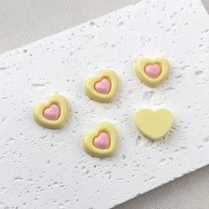 Close-up of yellow and pink resin heart charms for DIY crafts and phone case decor