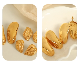 Détail de dix boucles d'oreilles dorées asymétriques torsadées sur tissu blanc