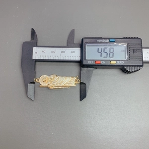 Measuring the St. Jude gold pendant with a digital caliper showing 45.8mm length