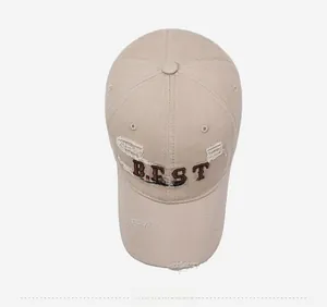 Top view of beige baseball cap with distressed details and BEST company embroidery