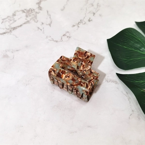 Detail of square acetate hair claw clip featuring brown and beige marble patterns