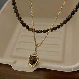 Detail of gold-plated necklace with oval tiger eye stone pendant and pavé crystals