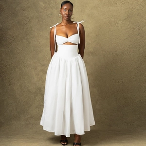Dettaglio di un set bianco a due pezzi con crop top a lacci e gonna lunga a pieghe