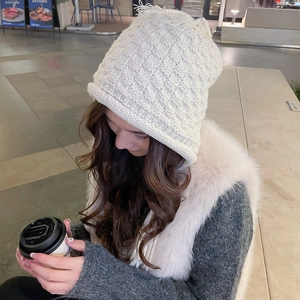 Close-up of white knit winter beanie with cat ear details and thick wool texture