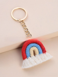 Detail view of handmade woven rainbow keychain with golden ring and soft white cotton tassels