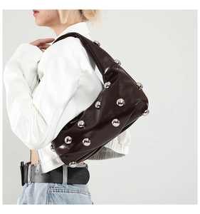 Detail of glossy leather underarm bag featuring large silver stud metal decorations