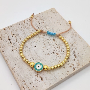 Close-up of handmade evil eye beaded bracelet with gold beads and adjustable cord