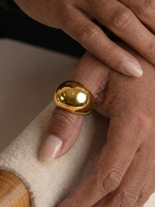 Close-up of polished 18k gold plated dome ring on hand with elegant minimalist design