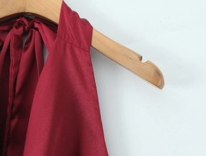 Détail du haut en satin bordeaux avec licou montrant le lustre soyeux sur cintre