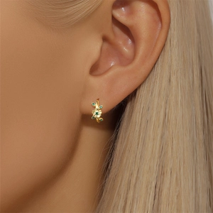 Close-up of a floral S925 silver earring with green zircon on a model's ear