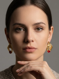 Close-up of elegant gold conch earrings featuring square red zircons on a model's ear