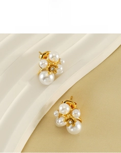Detailed macro view of golden flower stud earrings with white pearls and small crystal