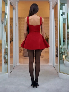 Vista posteriore di un mini abito rosso a trapezio senza schienale con collant e tacchi neri