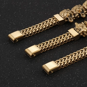Detailed view of gold lion head mesh bracelets with polished metallic texture on dark surface