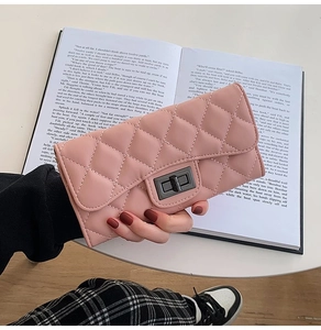 Detail of pink quilted wallet with metal turn-lock held over a vintage book