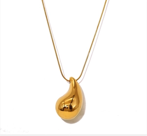 Macro shot of gold teardrop pendant with polished finish and sleek snake chain