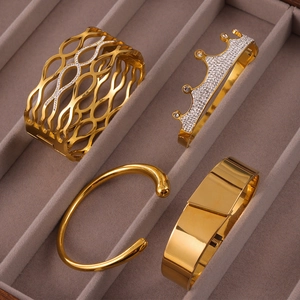 Set of four minimalist gold-plated titanium steel bangles displayed on grey velvet