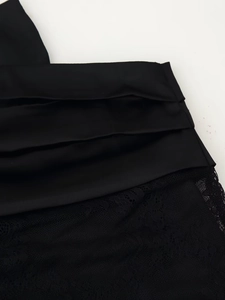 Vue détaillée du tissu en satin noir avec textures plissées et coutures en dentelle