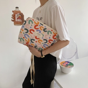 Dettaglio ravvicinato della borsa cosmetica trapuntata a fiori tenuta da una modella