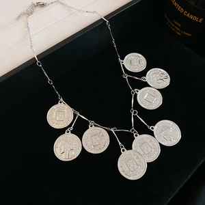 Macro detail of silver coin pendants with relief portraits on a vintage chain necklace