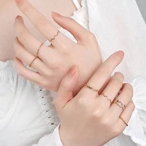Close-up of a layered gold ring set featuring heart shapes and woven bands on model hands