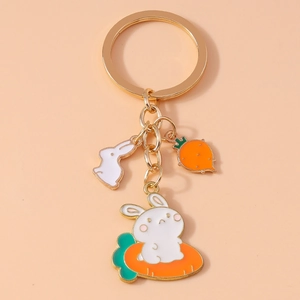 Close-up of a white rabbit and carrot enamel charm on a golden keychain accessory