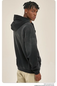 Detailweergave van gewassen zwarte hoodie met verlaagde schouders en zijaanzicht van model
