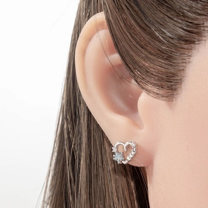 Silver hollow heart cartilage earring with blue flower zircon on model ear