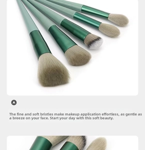 Close-up of five dual-tone green makeup brushes with soft gradient synthetic bristles