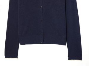 Detail of navy knit cardigan with buttons and white lace floral trim on cuffs