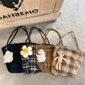 Detail of four plaid wool tote bags in various colors with cute plush animal keychains