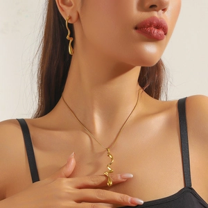 Close-up of gold-plated scalloped pendants on necklace and earrings worn by model