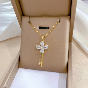 Detail of gold floral key necklace with sparkling zircon petals on a luxury silk background