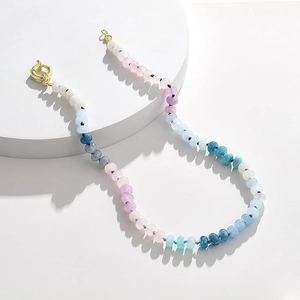 Detail of colorful bohemian stone bead necklace with gold clasp on white display