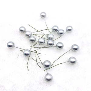 Close-up of shiny silver artificial berry ornaments on a white plush background