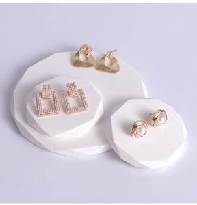Detail view of gold earrings with pearls on white geometric jewelry display stands