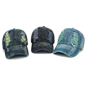 Detail of distressed denim baseball caps with frayed holes and contrast color stitching