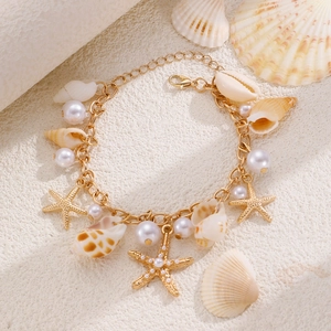 Detail of gold starfish and pearl charms on a bohemian beach style shell bracelet