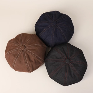 Detailed top view of denim beret hats in brown, navy, and grey with contrast stitching