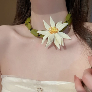 Detail of green resin bead necklace with a large white 3D flower pendant on a model