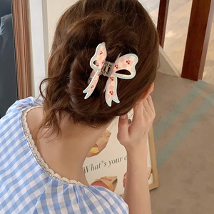 Pink checkered bow hair claw with cherry pattern worn on a model's hairstyle