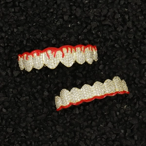 Macro detail of gold hip hop grillz with red enamel drip and cubic zirconia stones