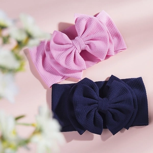 Close-up of pink and navy waffle knit baby headbands with large bows on a floral background